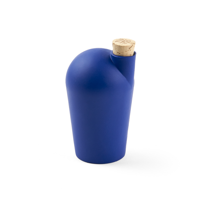 A hand holding a dark blue carafe with a cork stopper.