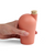 A hand holding a melon colored carafe with a cork stopper.