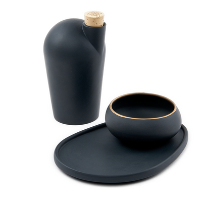 A blue carafe next to a black pairing plate and matching copita.