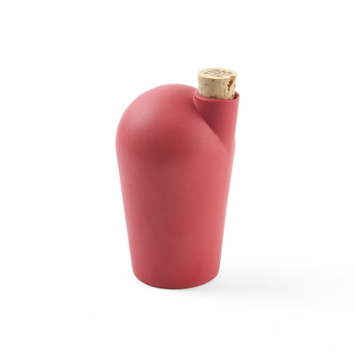 A three-quarter view of a small red porcelain carafe