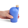 A hand holding a blue carafe with a cork stopper.