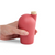 A hand holding a red carafe with a cork stopper.
