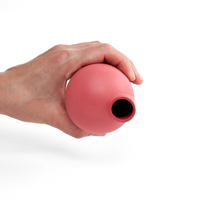 A hand holding a red carafe at an angle to show the top view and pour spout.