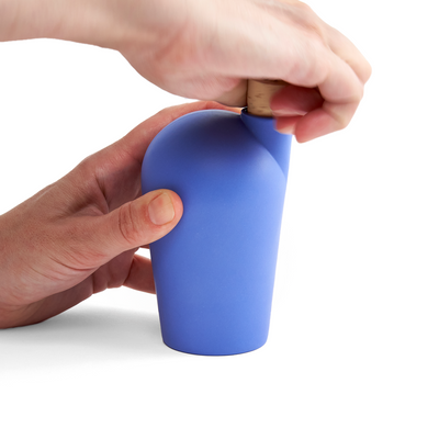 Two hands holding a blue carafe uncorking the top.