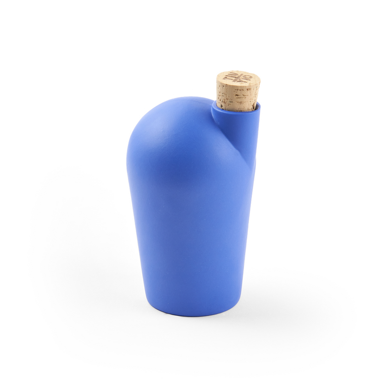 A hand holding a blue carafe with a cork stopper.