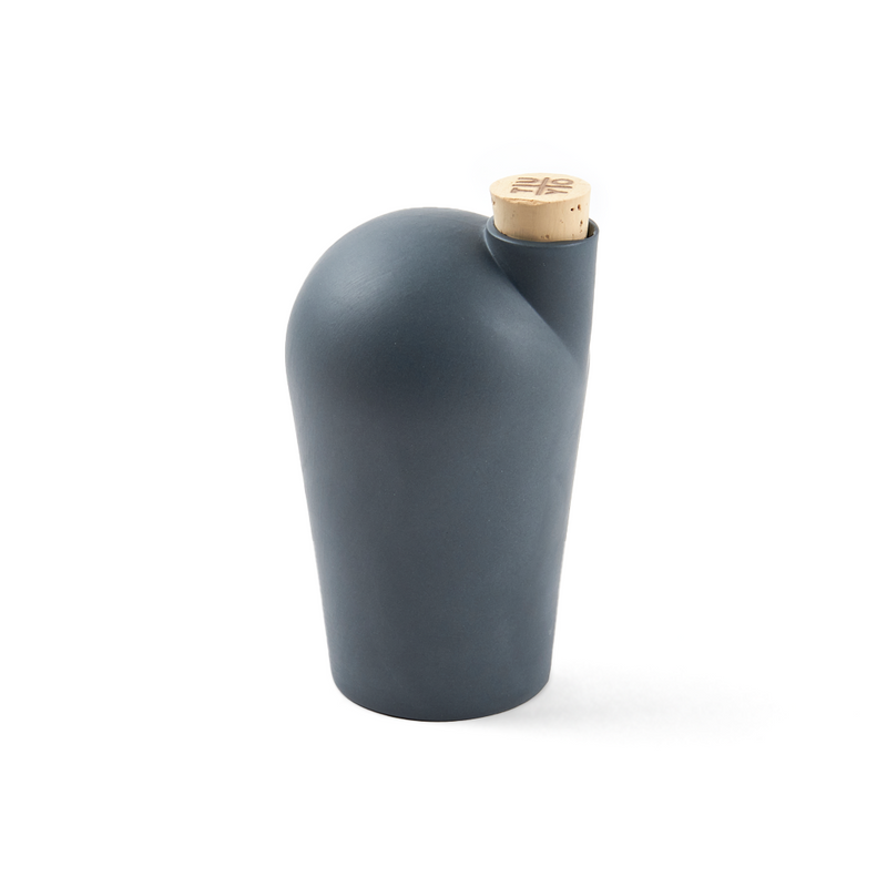 A hand holding a dark grey carafe with a cork stopper.