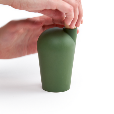 Two hands holding a green carafe uncorking the top.