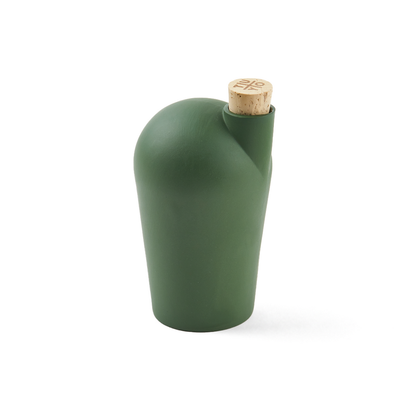 A hand holding a green carafe with a cork stopper.