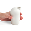A side view of a hand holding a porcelain white carafe.
