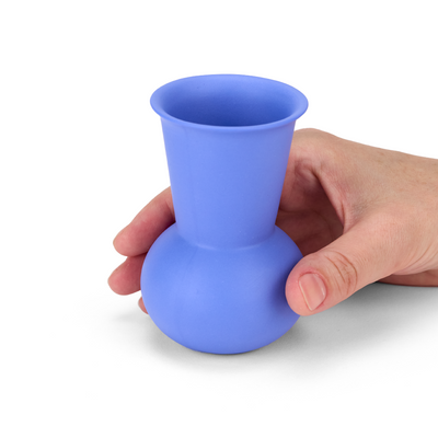 A hand holding a blue TUYO tequila sipping glass