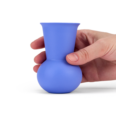 A hand holding a blue colored TUYO tequila sipping glass