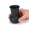 A hand holding a black charcoal  tuyo tequila sipping glass