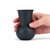 A hand holding a  black charcoal colored tequila sipping glass