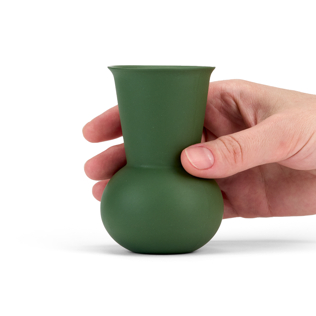 A hand holding a Green colored TUYO tequila sipping glass