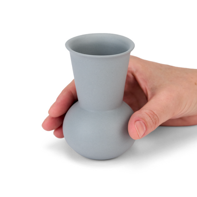 A hand holding a Light Grey  TUYO tequila sipping glass