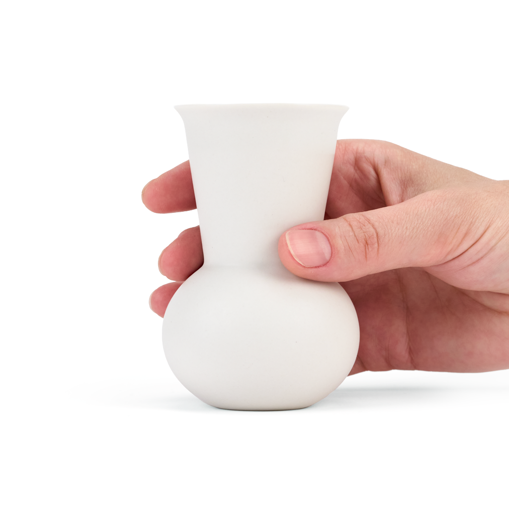 A hand holding a White colored TUYO tequila sipping glass