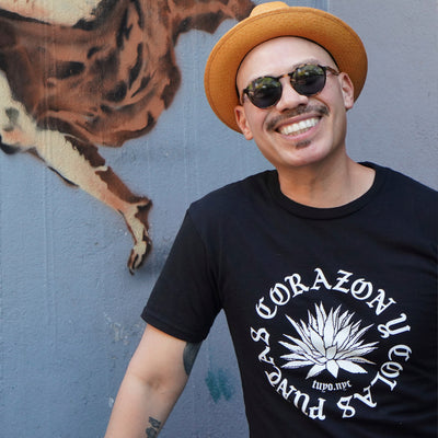 Oscar is wearing a size small black organic cotton tshirt silkscreened with an agave in the center in white ink and the words Puntas, Corazon y Colas.
