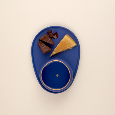 One dark blue pairing plate and copita with small food items on the plate: cheese and chocolate!