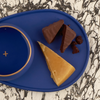 Close up of dark blue pairing plate, matching copita and food items.
