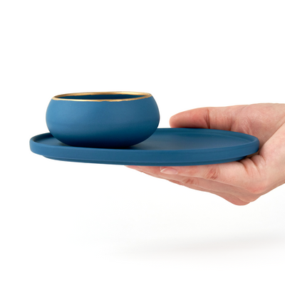 hand holding our ​​dark sea green pairing plate with matching dark sea green and gold copita